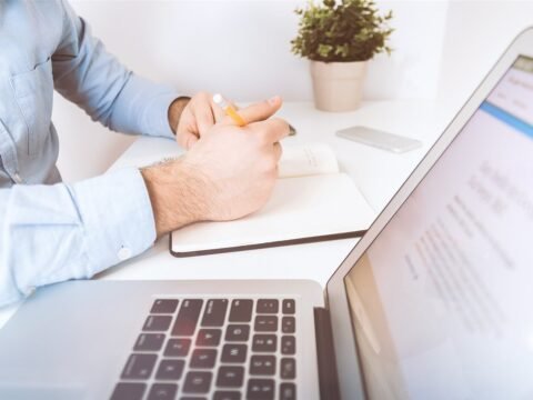 Writing notes beside a laptop