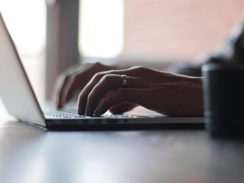 Hands typing on a laptop keyboard