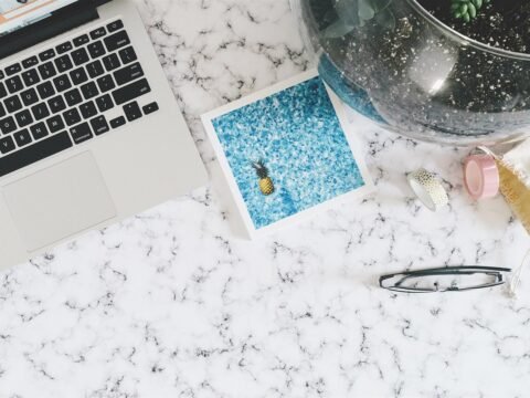 Laptop, printed photo and glasses on a marble desk