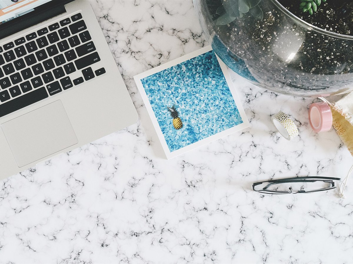 Laptop, printed photo and glasses on a marble desk